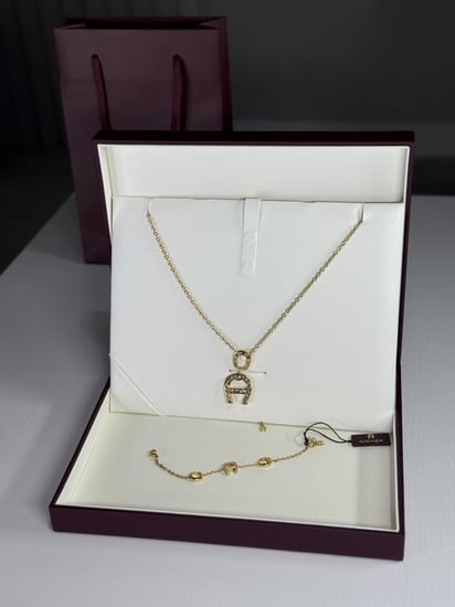 طقم اجنر سلسلة و اسوار ذهبي بالعلامه المرصع بالكريستال A670128. B20 Aigner gold necklace and bracelet set women