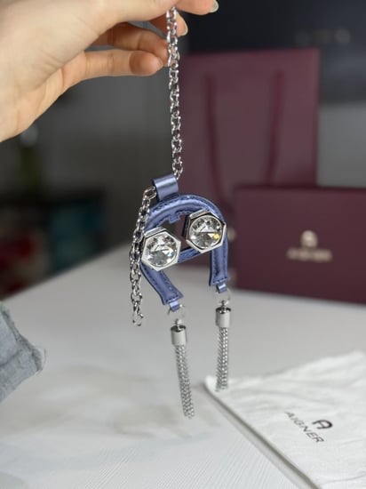 تعليقة اجنر باللون الازرق المعدني اللامع على شكل حذوه من الجلد الوردي Aigner metallic blue charm with stones and tassel's