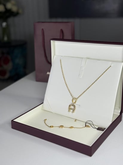 طقم اجنر سلسلة و اسوار ذهبي بالعلامه المرصع بالكريستال A670128. B20 Aigner gold necklace and bracelet set women