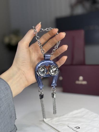 تعليقة اجنر باللون الازرق المعدني اللامع على شكل حذوه من الجلد الوردي Aigner metallic blue charm with stones and tassel's