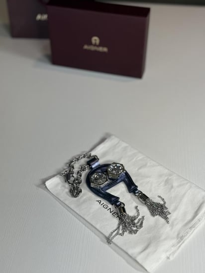 تعليقة اجنر باللون الازرق المعدني اللامع على شكل حذوه من الجلد الوردي Aigner metallic blue charm with stones and tassel's