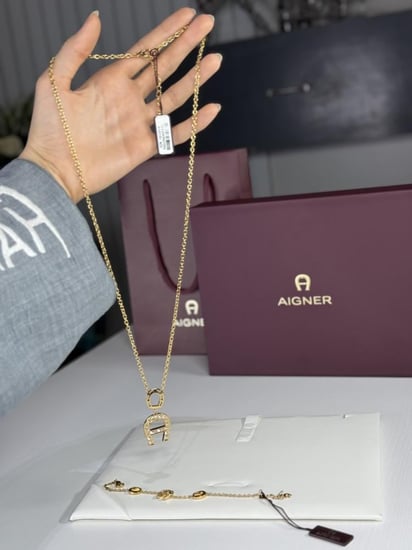 طقم اجنر سلسلة و اسوار ذهبي بالعلامه المرصع بالكريستال A670128. B20 Aigner gold necklace and bracelet set women