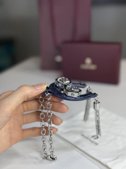تعليقة اجنر باللون الازرق المعدني اللامع على شكل حذوه من الجلد الوردي Aigner metallic blue charm with stones and tassel's