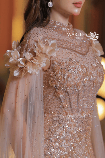 فستان سهرة فاخر بترتر ذهبي وأكمام شفافة مزينة بالورود