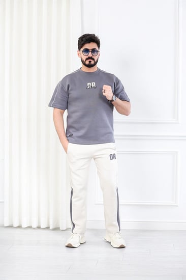 طقم رجالي اوفر سايز نص كم بنطال طويل مزين بطبعة بأحرف صغيرة على الجهة الأمامية من الطقم وكبيرة على ظهر التيشرت