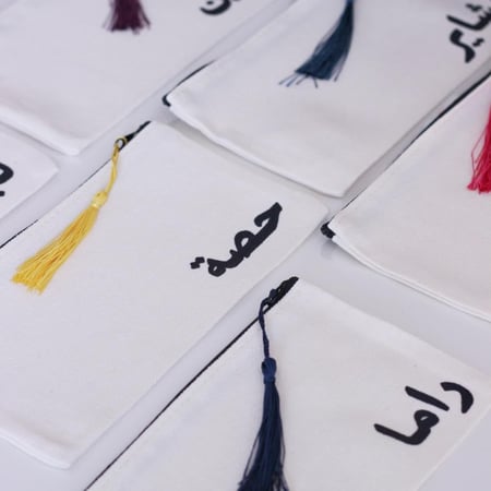 محفظة صغيرة مع كتابة الاسم باللون الأسود ( التعليقة بألوان عشوائية)