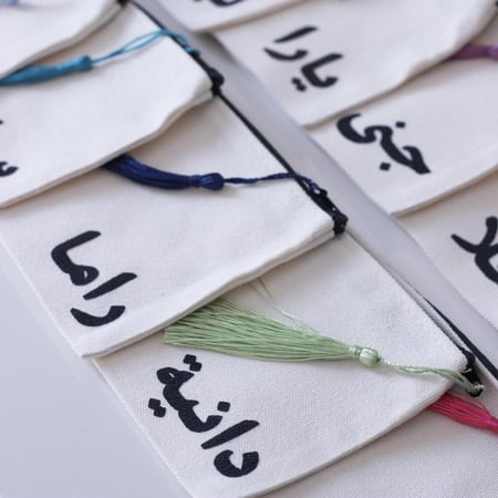 محفظة صغيرة مع كتابة الاسم باللون الأسود ( التعليقة بألوان عشوائية)