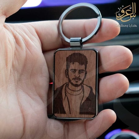 ميدالية مفاتيح خشبية محفور عليها صورة شاب داخل إطار معدني أنيق