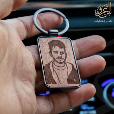 ميدالية مفاتيح خشبية محفور عليها صورة شاب داخل إطار معدني أنيق