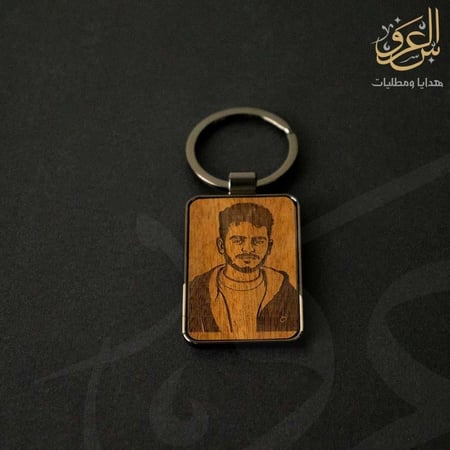 ميدالية مفاتيح خشبية محفور عليها صورة شاب داخل إطار معدني أنيق