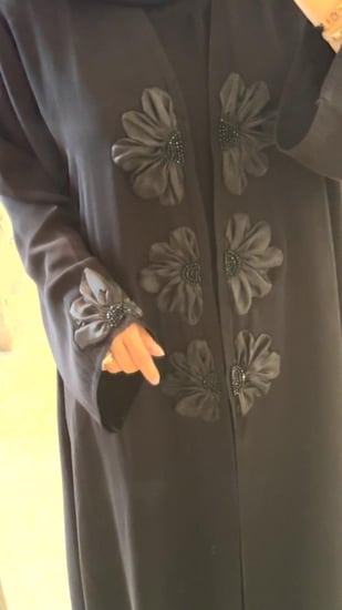 عباية سوداء مزينه بالورود وفيها قطعه داخليه مثل الفستان