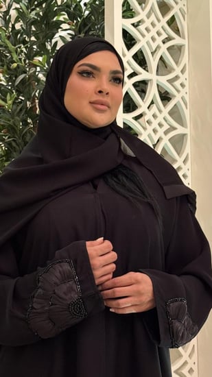 عباية سوداء مزينه بوردة كبيرة من الجنب ومن الأكمام