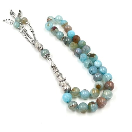 منظر قريب للخرز المصقول والشرابة الفضية ذات التفاصيل المعدنية