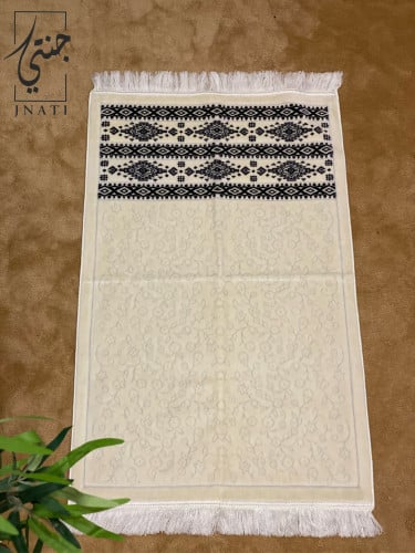 Beige prayer rug with black designs at the edge of...
