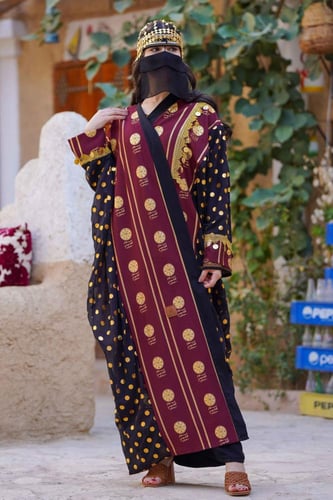 بشت أسود مع ياقة عنابي متزين بهوية يوم التأسيس