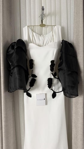 فستان أبيض ناعم بأكمام سوداء منفوخة وزهور بارزة عن...