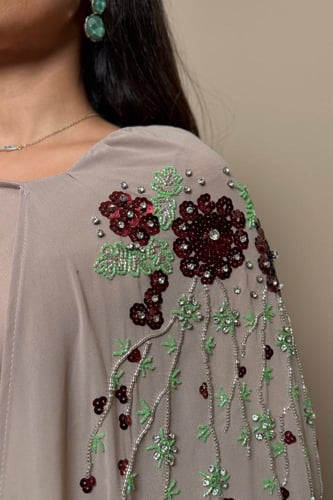 فستان ترابي بتطريز ورود عنابي وتفاصيل خرز فاخرة