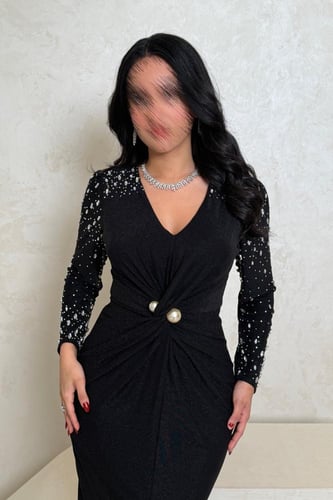 فستان أسود بلمعة ناعمة وتفاصيل مطرّزة بالأكمام