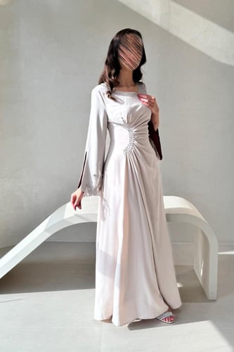 فستان بيج بتفاصيل لؤلؤية وأكمام خمري فاخرة