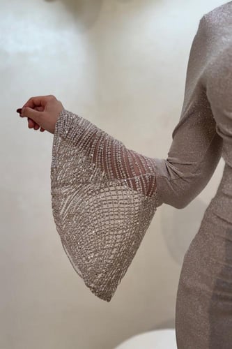 فستان سهرة ذهبي بقصة ضيقة وأكمام لامعة