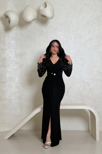 فستان أسود بلمعة ناعمة وتفاصيل مطرّزة بالأكمام