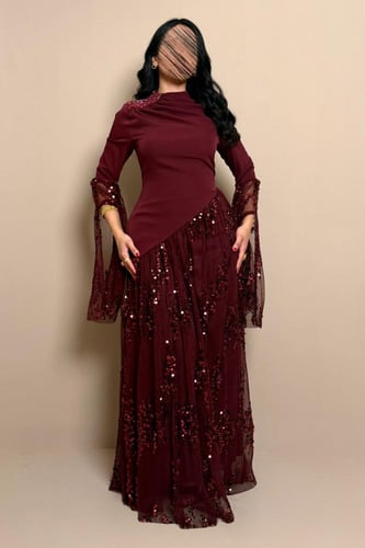 فستان سهرة عنابي بقصة مائلة وأكمام شفافة لامعة