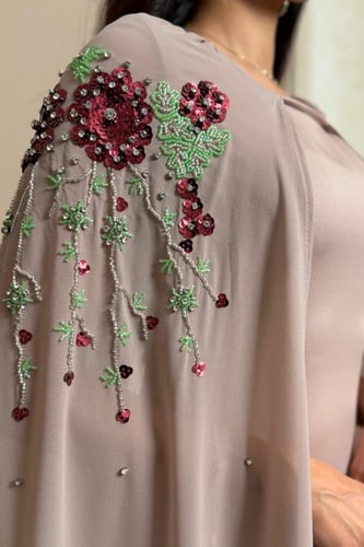 فستان ترابي بتطريز ورود عنابي وتفاصيل خرز فاخرة