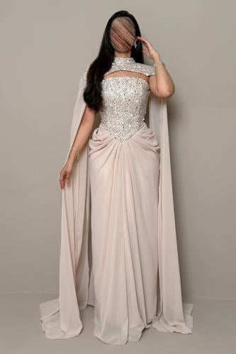 Long light nude dress with embroidered details and a flowing shawl.