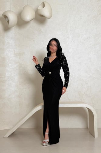 فستان أسود بلمعة ناعمة وتفاصيل مطرّزة بالأكمام