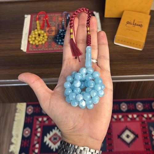 A prayer bead with a blue shell color and white cl...