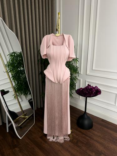 فستان سهرة فاخر باللون الوردي الناعم (Baby Pink)، يجمع بين قصّة الكورسيه المحددة وأناقة الشراشيب