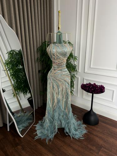 فستان طويل (Marmied) لونه أخضر نعناعي (mint green). يتميز بتصميم فريد يجمع بين الترتر اللامع والريش الناعم.