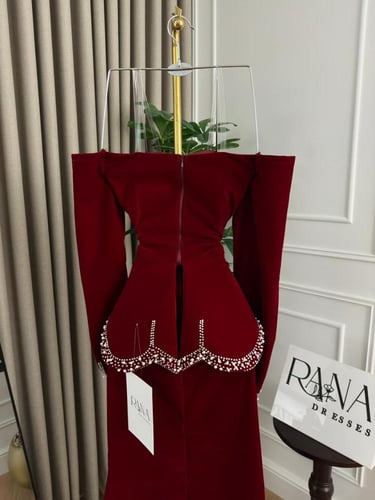 فستان أحمر ملكي بتفاصيل فاخرة وأكمام طويلة