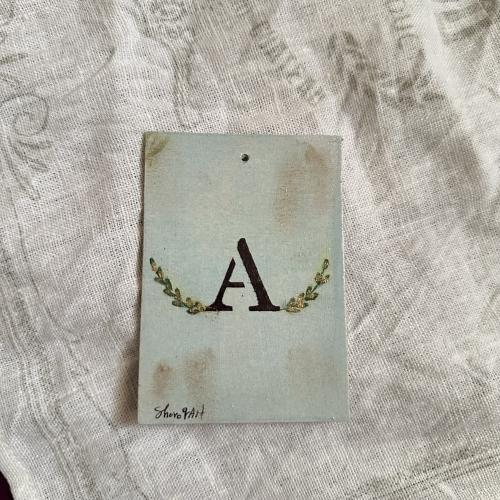 A wooden gilded herbal hanging with the letter A