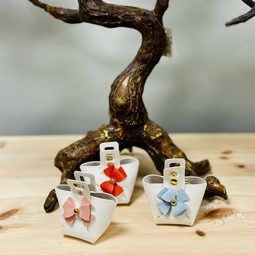 توزيعات جلد بشكل شنطة بلون اوف وايت وكبسات ذهبي و...