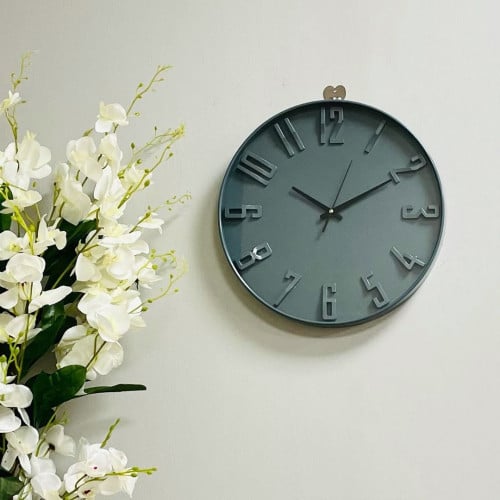 ساعة بلاستيك وزجاج دائرية بارقام بارزة باللون الرم...