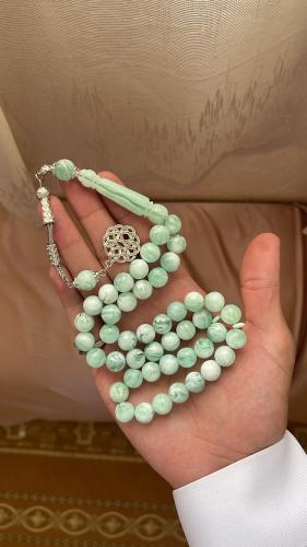 A turquoise-colored metal prayer bead rosary with...