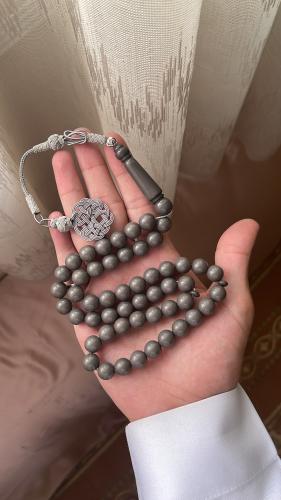 A prayer bead rosary with a cement-colored clip, t...