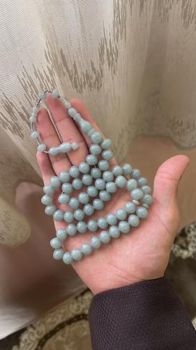 A turquoise-colored prayer bead with a tear-shaped...