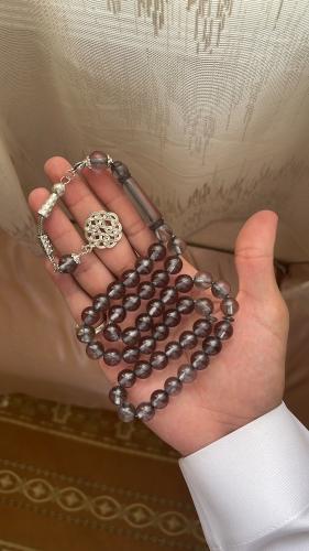A transparent smoky-colored plastic prayer bead st...