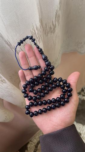 A prayer bead with a navy blue color, tear-shaped,...