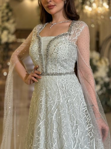 فستان سهرة بلون أخضر ثلجي بقصة مع كاب شفاف مرصّع و...