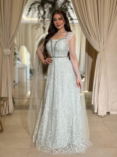 فستان سهرة بلون أخضر ثلجي بقصة مع كاب شفاف مرصّع و...