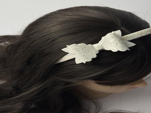 طوق بلاستك مزين بفيونكة جلد أبيض وفضي