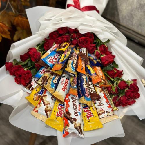 تشكيلة منوعة من الحلويات مرتبة داخل بوكيه مع ورد ب...