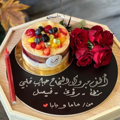 كيكة الفواكه من حلويات نعمة على استاند خشبي مع إمك...