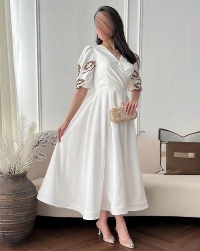 فستان أبيض ملكي بتصميم راقٍ ولمسات ذهبية فاخرة