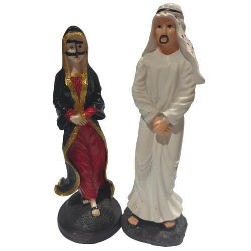 هذه تحفة تذكارية مصغرة تمثل زوجين يرتديان الأزياء التقليدية الخليجية رجل يرتدي الثوب الأبيض والشماغ التقليدي، وإلى جانبه امرأة ترت...