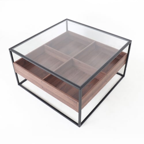 طاولة قهوة وسط بسطح زجاجي وقواعد معدن