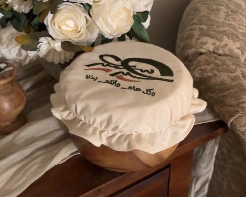 وعاء سَخاء بغطاء قماشي مطرز بعبارة "عيد سعيد"